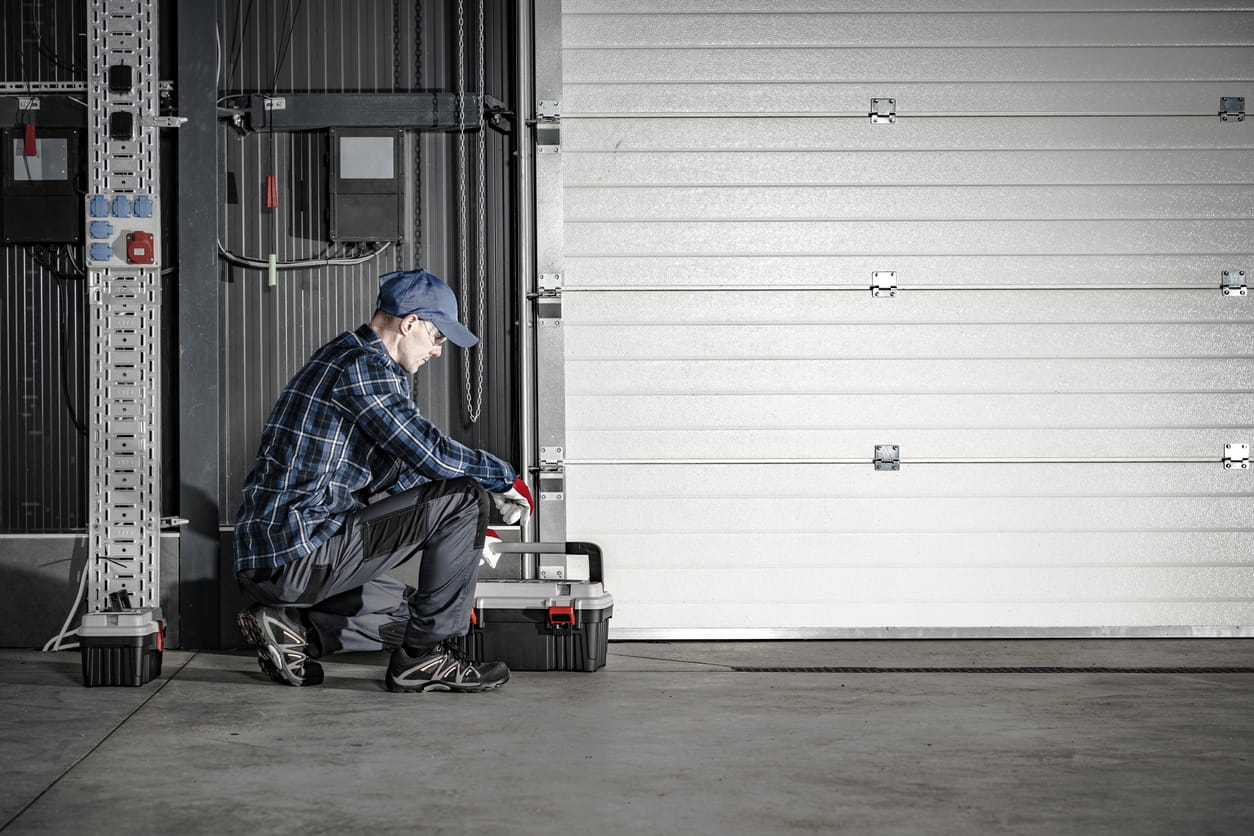Technician inspecting loading dock equipment and warehouse door during troubleshooting and repair service at a Virginia distribution facility.