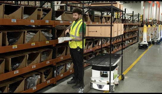 Warehouse robot assisting worker with order picking.