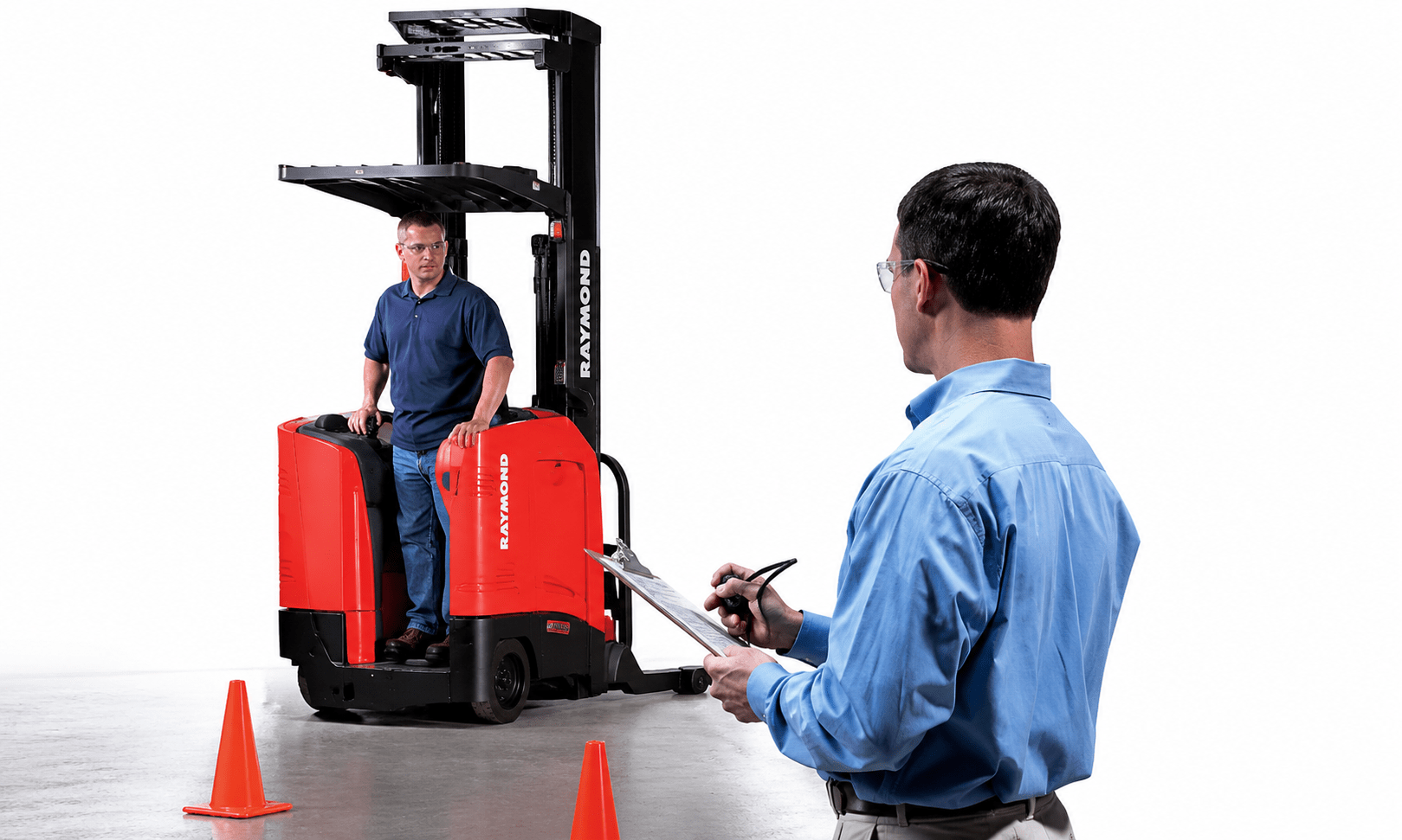 Instructor observing and evaluating a forklift operator on a Raymond forklift during warehouse safety training with traffic cones marking the training course.